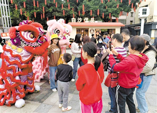 游客在長堤歷史文化街區(qū)與醒獅合影。何雯意